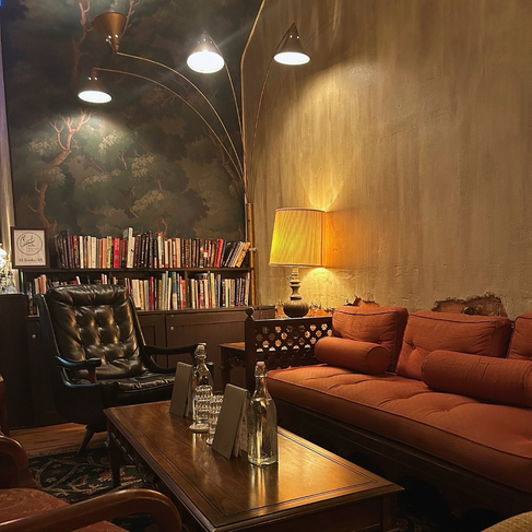 Lounge corner with forest mural, leather sofa, and reading lamps